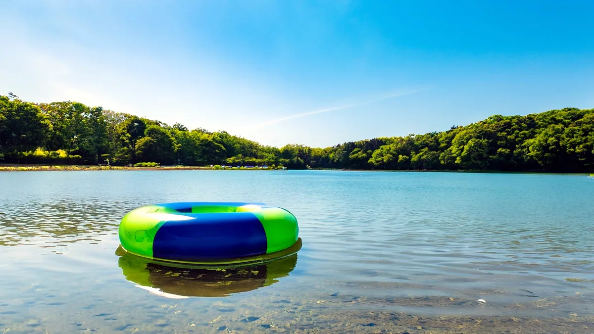 An inflated towable raft floating on a glassy lake, its handles just above the waterline.