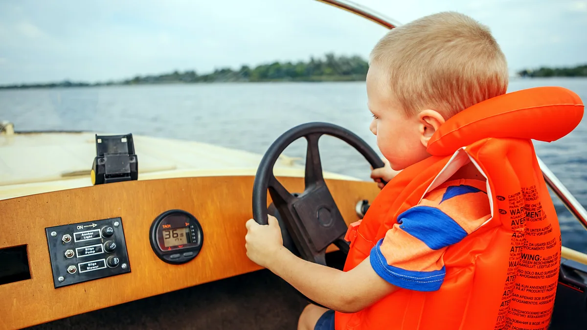 A bright orange life vest draped over a boat seat, the sun glinting off the water beyond.