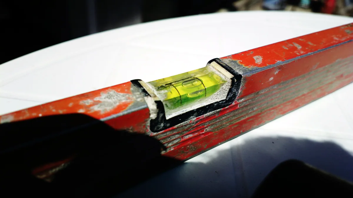 A wax iron leaving a glossy trail across the base of an upside-down snowboard.