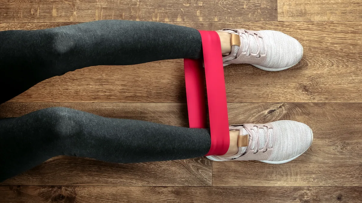 A looped resistance band stretched across the wooden floor of a small training room.
