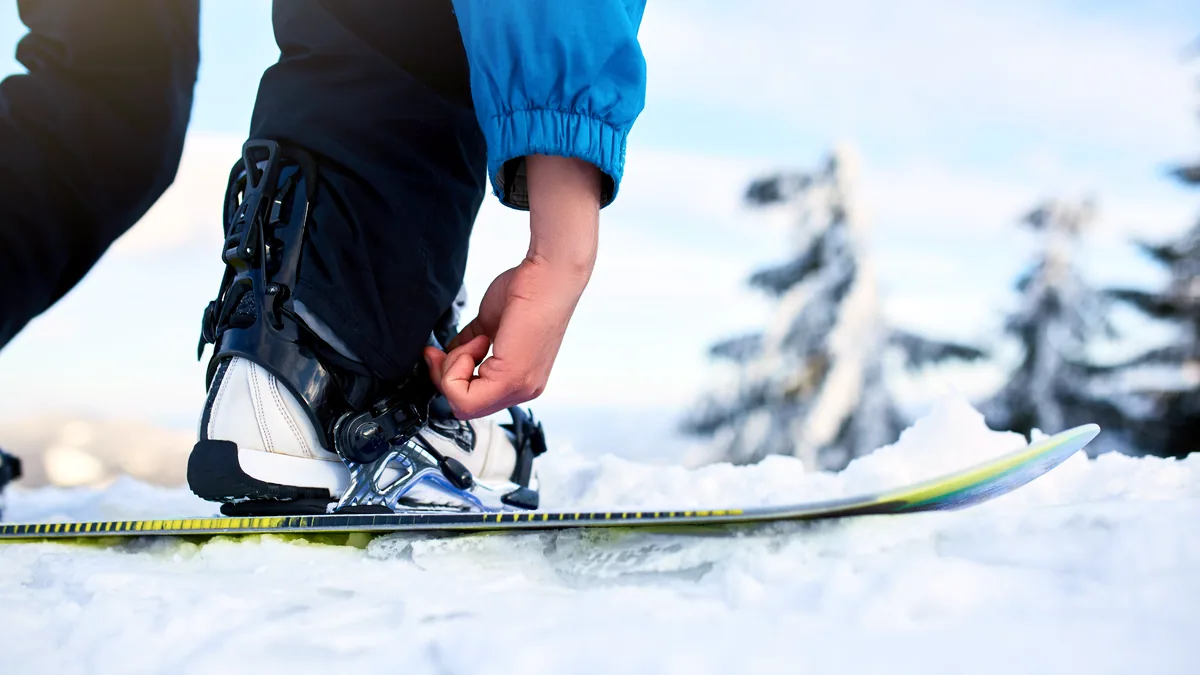 A snowboard with bindings and a pair of boots resting on a patch of fresh snow.