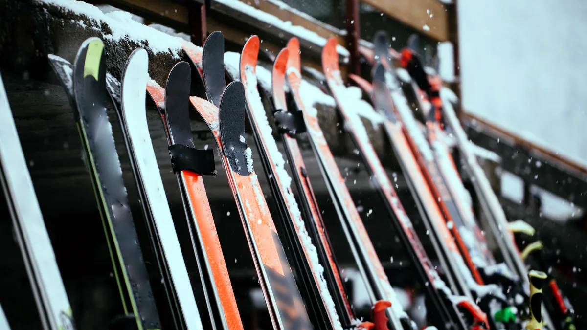 Rows of rental snowboards racked upright in a dimly lit shop, price tags on each board.