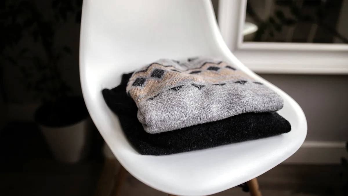 A heavy grey fleece hoodie crumpled over the back of a wooden chair in a lodge.
